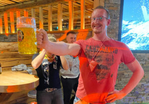 Physiotherapeut Tobias hält einen Bierkrug auf Zeit in der Hand als Teamchallenge bei einer Weihnachtsfeier